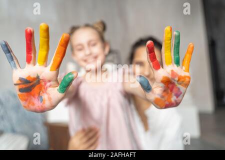 Small funny girl showing painted coloured palms to camera Stock Photo