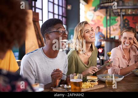 Group Of Young Friends Meeting For Drinks And Food In Restaurant Stock Photo