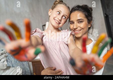 Cute child showing painted coloured palms to camera Stock Photo