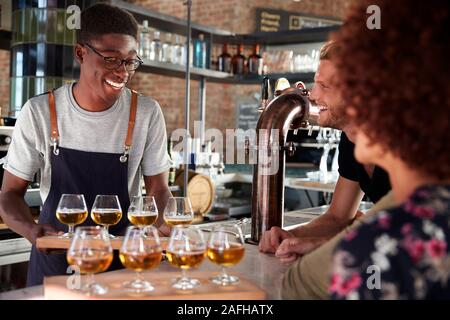 Waiter Serving Group Of Friends Beer Tasting In Bar Stock Photo