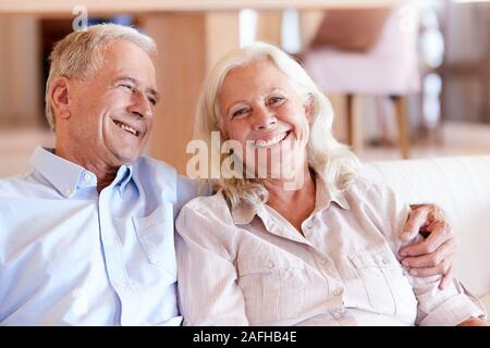 Happy senior white couple sitting at home embracing, front view, close up Stock Photo