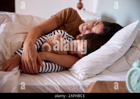 Mid adult woman sleeping in bed with her four year old son, waist up, close up