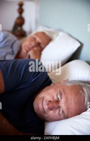 Senior white couple asleep in their bed, close up, vertical Stock Photo