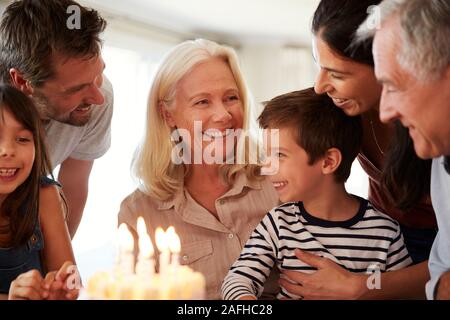 Four year old white boy and his family celebrating with a birthday cake and lit candles, close up Stock Photo