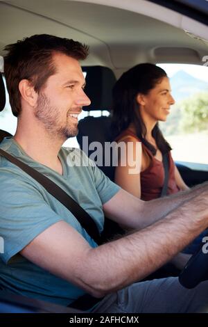Smiling mid adult white couple driving in their car, close up, side view, vertical Stock Photo
