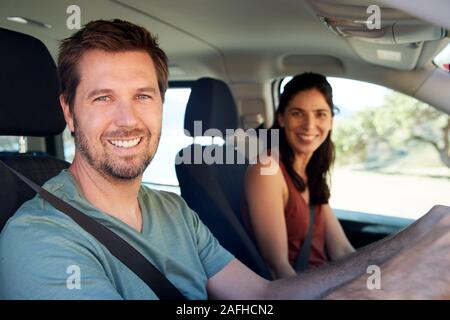 Smiling mid adult white couple driving in their car smiling to camera, close up, side view Stock Photo