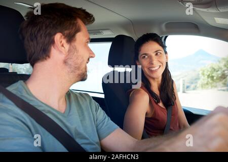 Happy mid adult white couple driving in their car, smiling at each other, close up, side view Stock Photo