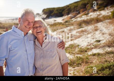 Senior white couple standing on a beach embracing and smiling to camera, close up Stock Photo