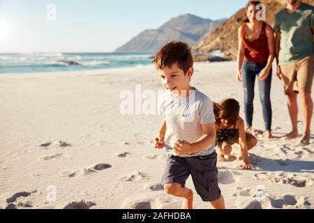 Happy young white family on holiday exploring a beach together, full length, close up