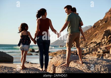 Mid adult parents and their two pre-teen children standing on beach admiring the view, full length