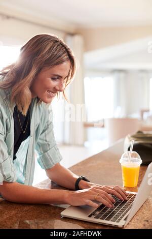 Millennial white woman checking fitness data on laptop at home after the gym, vertical Stock Photo