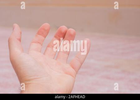 Conceptual open hand reaching out on soft orange background. Openness, giving, assistance and helping concepts. Stock Photo