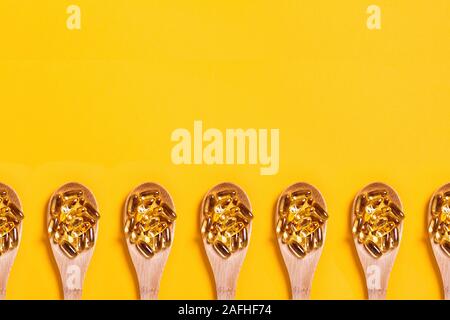 Fish oil capsules in a wooden cup on a blurred orange background.Omega ...