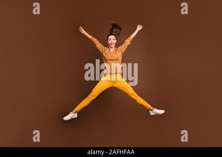 Full length body size photo of cheerful positive cute nice sweet pretty girl expressing overjoying emotions jumping in star shape isolated over brown Stock Photo