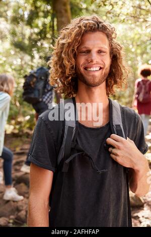 Waist up portrait of smiling millennial white man hiking in a forest, close up, vertical Stock Photo