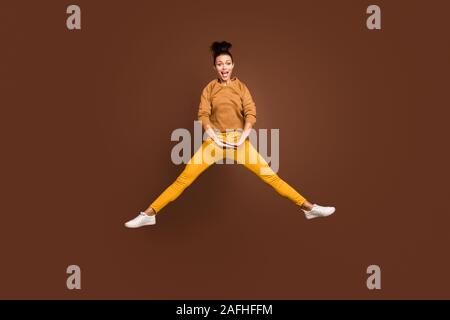 Full length body size photo of cheerful positive cute sweet pretty girl wearing yellow pants trousers doing splits in white footwear jumping isolated Stock Photo