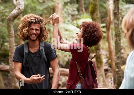 Millennial African American woman taking burrs out of her male friend’s hair, close up Stock Photo