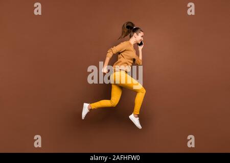 Full length body size side profile photo of young girl speaking by her phone running towards discounted shopping mall wearing trousers pants isolated Stock Photo