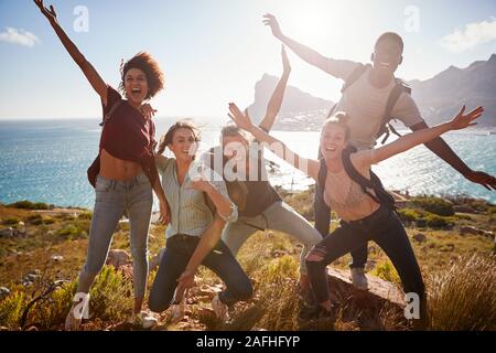 Millennial friends on a hiking trip reach the summit and have fun posing for photos Stock Photo