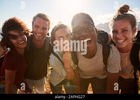 Young adult friends on a hike celebrate reaching the summit, smiling to camera, close up Stock Photo