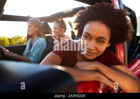 Millennial African American woman on road trip with friends, leaning out of the car window, close up Stock Photo