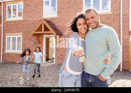 Portrait Of Family Holding Keys Standing Outside New Home On Moving Day Stock Photo