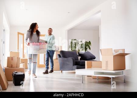 Smiling Couple Carrying Boxes Into New Home On Moving Day Stock Photo