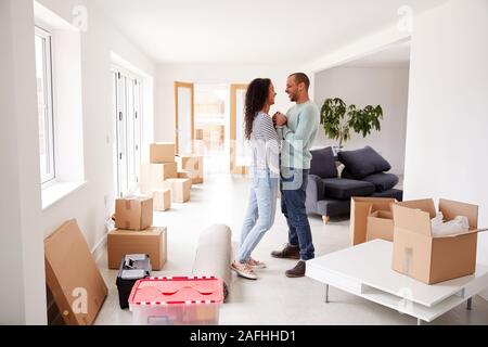 Loving Couple Surrounded By Boxes In New Home On Moving Day Stock Photo