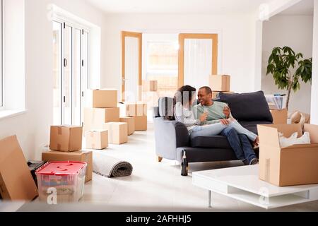 Couple Taking A Break And Sitting On Sofa Celebrating Moving Into New Home With Champagne Stock Photo