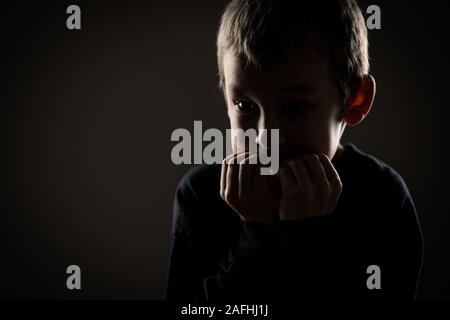 Grief-stricken little boy - feeling intense sorrow, remorse, sadnesss - studio portrait - vivid emotions series Stock Photo