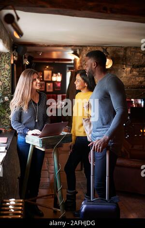 Receptionist Welcoming Guest Couple As They Check Into Hotel Stock Photo