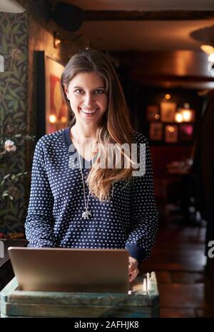 Portrait Of Female Receptionist Working On Laptop At Hotel Check In Stock Photo
