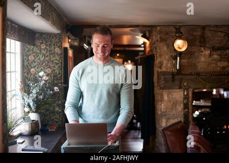 Male Receptionist Working On Laptop At Hotel Check In Stock Photo