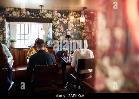 Group Of People Eating In Restaurant Of Busy Traditional English Pub Stock Photo