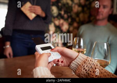 Close Up Of Customer In Restaurant Entering PIN Number Into Credit Card Terminal Stock Photo