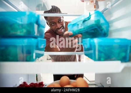 View Looking Out From Inside Of Refrigerator As Man Takes Out Healthy Packed Lunch In Container Stock Photo