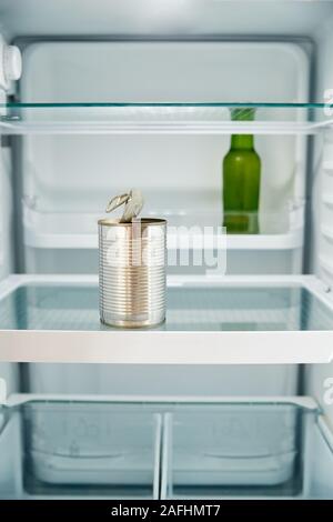 View Looking Inside Refrigerator Empty Except For Open Tin Can And Bottle Of Beer On Shelf Stock Photo