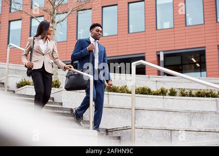 Businessman And Businesswoman Commuting To Work Walking Down Steps Outside Office Building Stock Photo