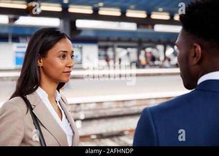 Businessman And Businesswoman Commuting To Work Talking On Railway Platform Waiting For Train Stock Photo