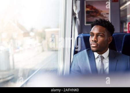 Businessman Sitting In Train Commuting To Work Looking Out Of Window Stock Photo