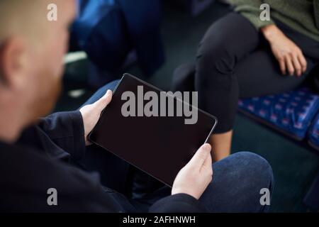 Close Up Of Male Passenger Sitting In Train With Digital Ticket On Tablet Computer Stock Photo