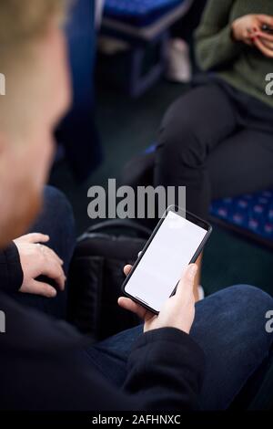Close Up Of Male Passenger Sitting In Train With Digital Ticket On Mobile Phone Stock Photo