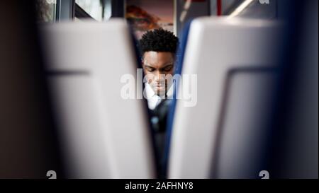 Businessman Sitting In Train Commuting To Work Viewed Between Two Seats Stock Photo