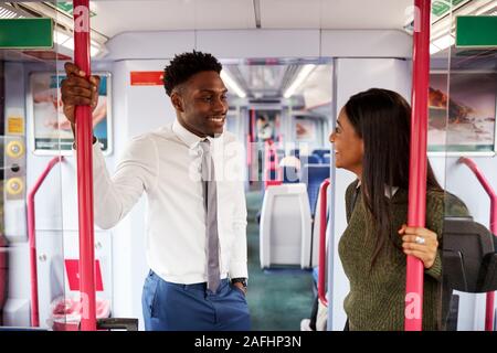 Business Passengers Standing In Train Commuting To Work Having Discussion Stock Photo