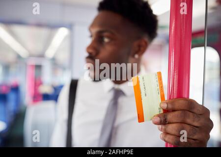 Businessman Standing In Train Commuting To Work Holding Ticket Stock Photo