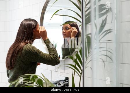 Businesswoman At Home Putting On Make Up In Mirror Before Leaving For Work Stock Photo