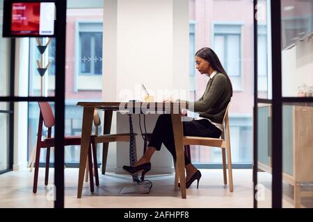 Businesswoman Working On Laptop At Desk In Meeting Room Stock Photo