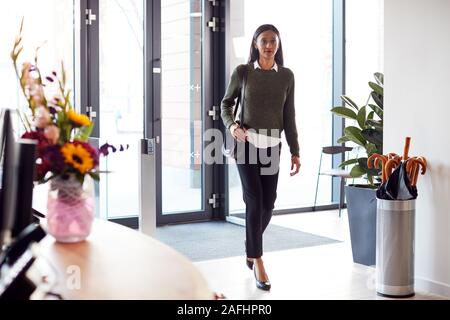 Businesswoman Arriving For Work At Office Walking Through Door Stock Photo