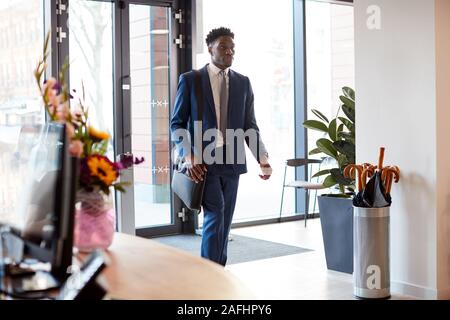Businessman Arriving For Work At Office Walking Through Door Stock Photo