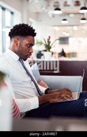 Businessman Working On Laptop At Desk In Shared Workspace Office Stock Photo